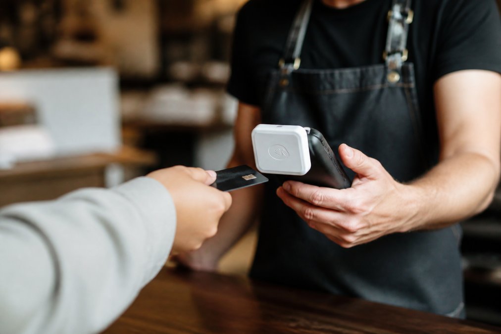 Small business owner using a secure mobile payment reader to process a customer's credit card at a retail counter