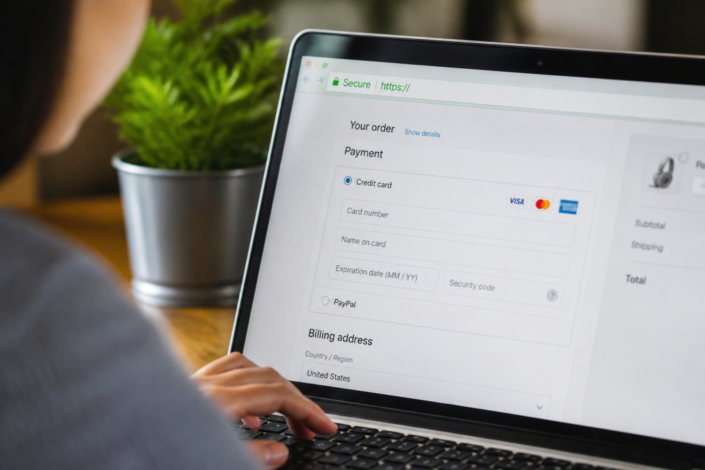 Close-up of a laptop screen showing a secure checkout page with padlock icon visible in the address bar, customer entering payment information with focus on the security indicators and green address bar