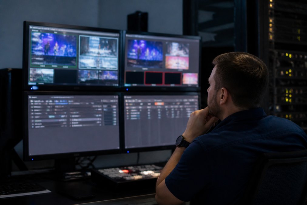 Technician monitoring latency and bandwidth metrics on a secure streaming dashboard in a control room