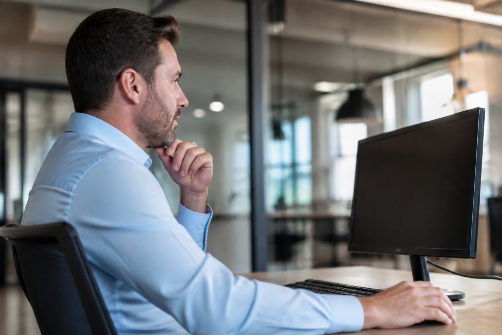 Responsable de formation consultant un tableau de bord de gestion des accès sur un écran d'ordinateur dans un environnement professionnel moderne, avec des graphiques de permissions et des listes d'utilisateurs visibles