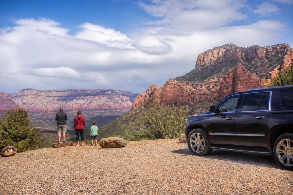 Travelers stretching at a scenic red rock overlook on the drive from Sedona to Grand Canyon.