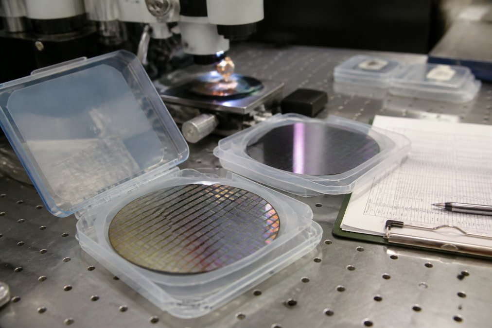 Close-up of precision calibration wafers on a metrology workstation with measurement instruments and quality control documentation visible
