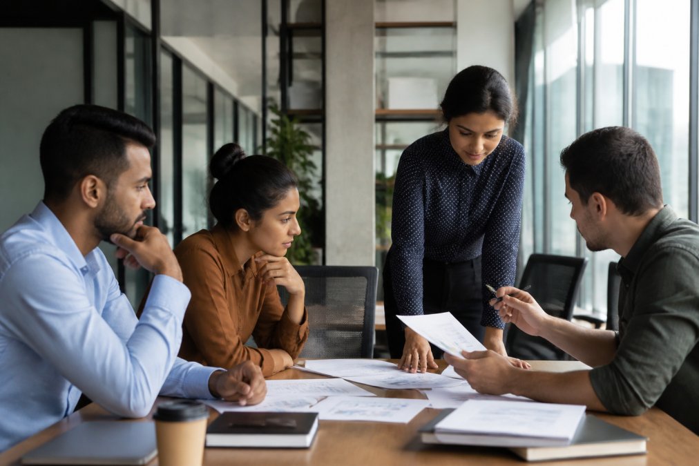 Marketing team reviewing analytics dashboards and SEO performance metrics on multiple screens in a modern office workspace with natural lighting