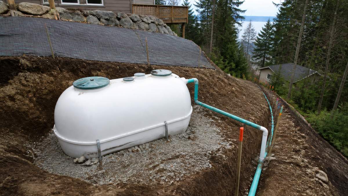 Diagram of septic system installation on sloped property showing tank placement, pipe slope, and erosion control.