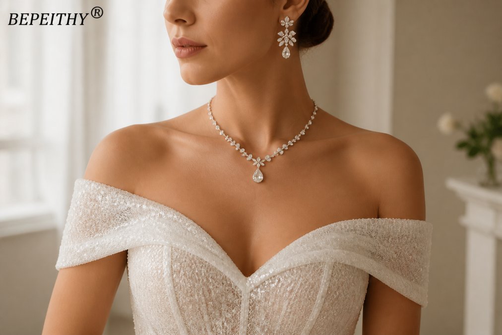 Close-up of a bride's neck, shoulders, and upper chest displaying an elegant bridal jewelry set with a delicate necklace and coordinating drop earrings against her ivory lace wedding dress