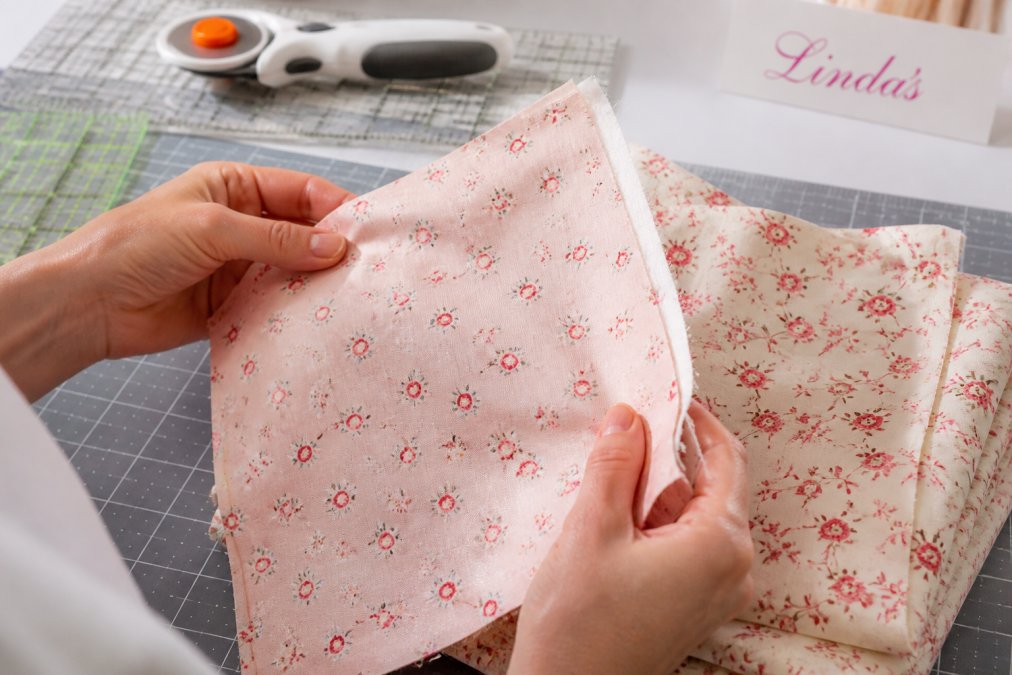 Quilter examining cotton fabric texture to compare shabby fabrics vs connecting threads quality