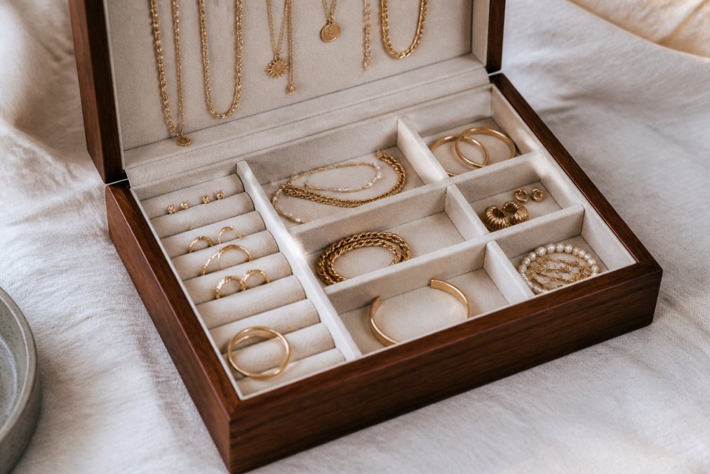 Sieraden netjes georganiseerd in een elegante houten sieradendoosje met zachte voering, met gescheiden vakken voor verschillende sieraden