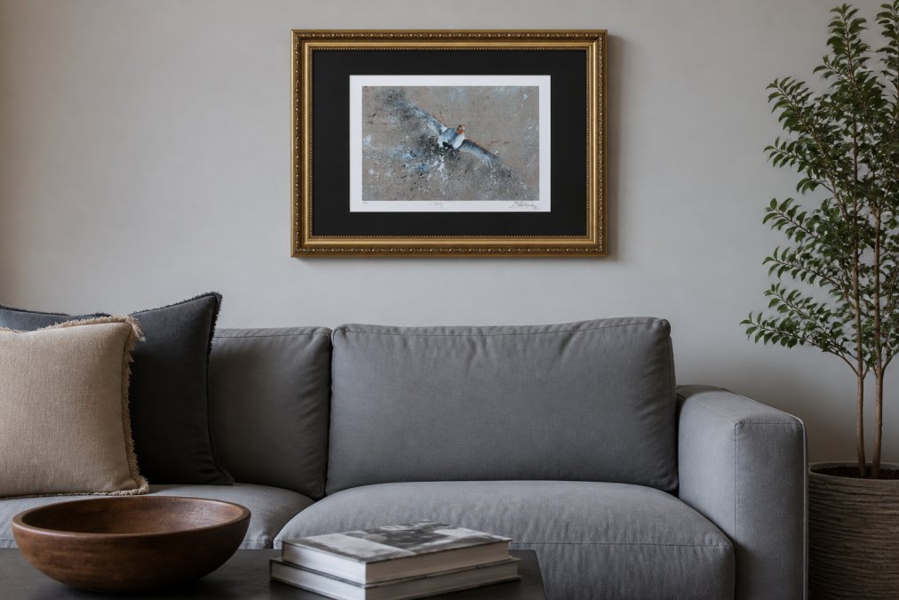 Contemporary living room with a framed English partridge print displayed above a minimalist grey sofa, showing how wildlife art complements modern furnishings and neutral wall tones