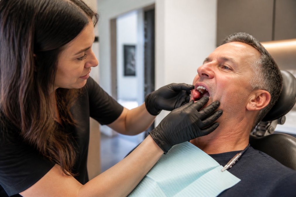 Professional demonstrating gum examination around dental implant site with good lighting in clinical setting