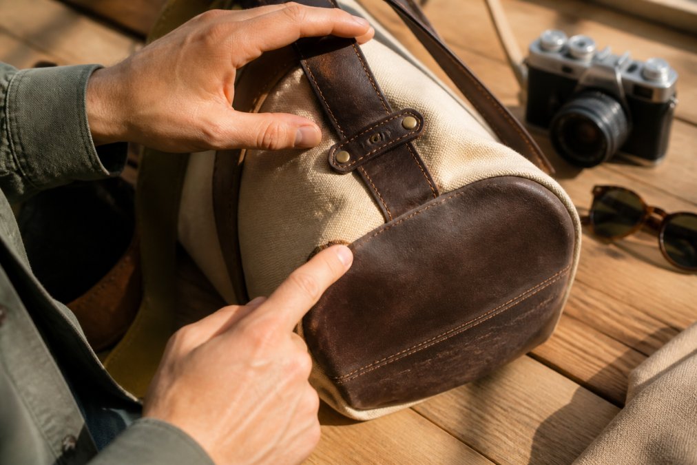 Hands examining a personalized gift item close-up, pointing to made in USA label while checking stitching quality, material weight, and hand-finished details under natural light