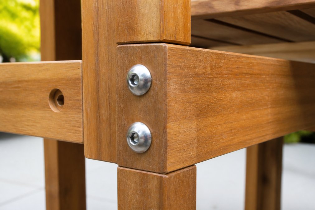Macro photograph of stainless steel bolts and fasteners on an outdoor furniture frame, showing polished rust-proof hardware detail against wooden frame