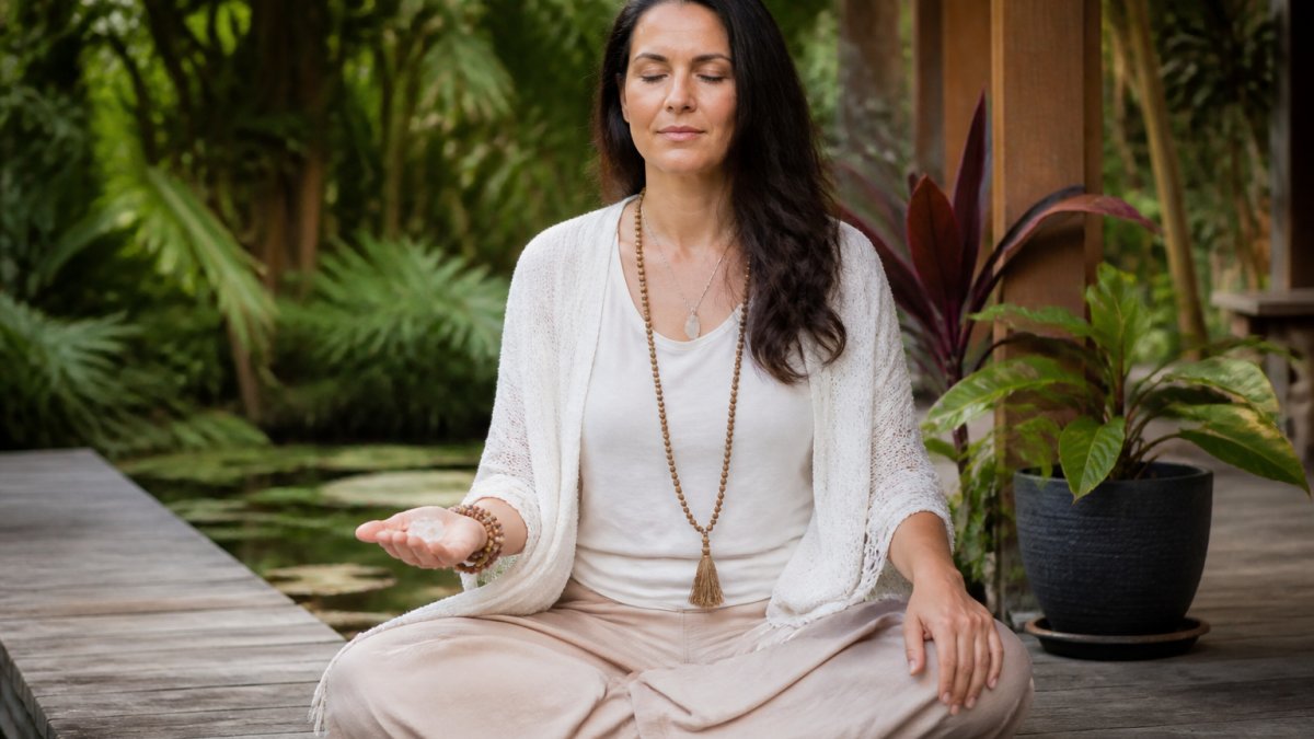Person meditating in a serene garden while holding a crystal to maintain balance and inner peace