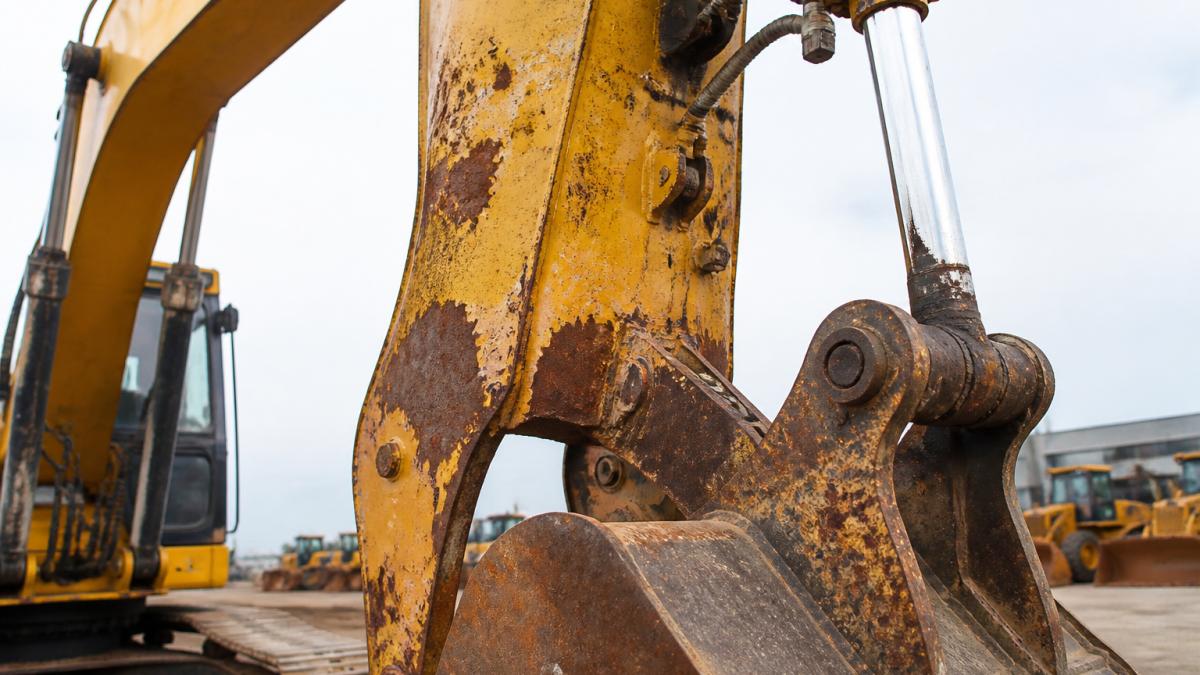 Infographic diagram highlighting rust and paint damage as key signs of wear used excavators display on booms and buckets.