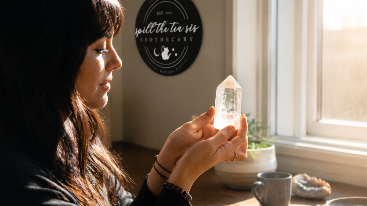 Close-up of hands gently holding a clear quartz crystal in natural sunlight streaming through a window, with warm light reflecting off the stone's facets and a calm, intentional expression on the person's face