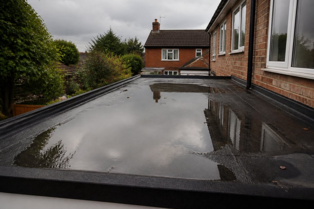 Standing water pooling in a depression on a flat roof, one of the key signs your flat roof needs replacing.