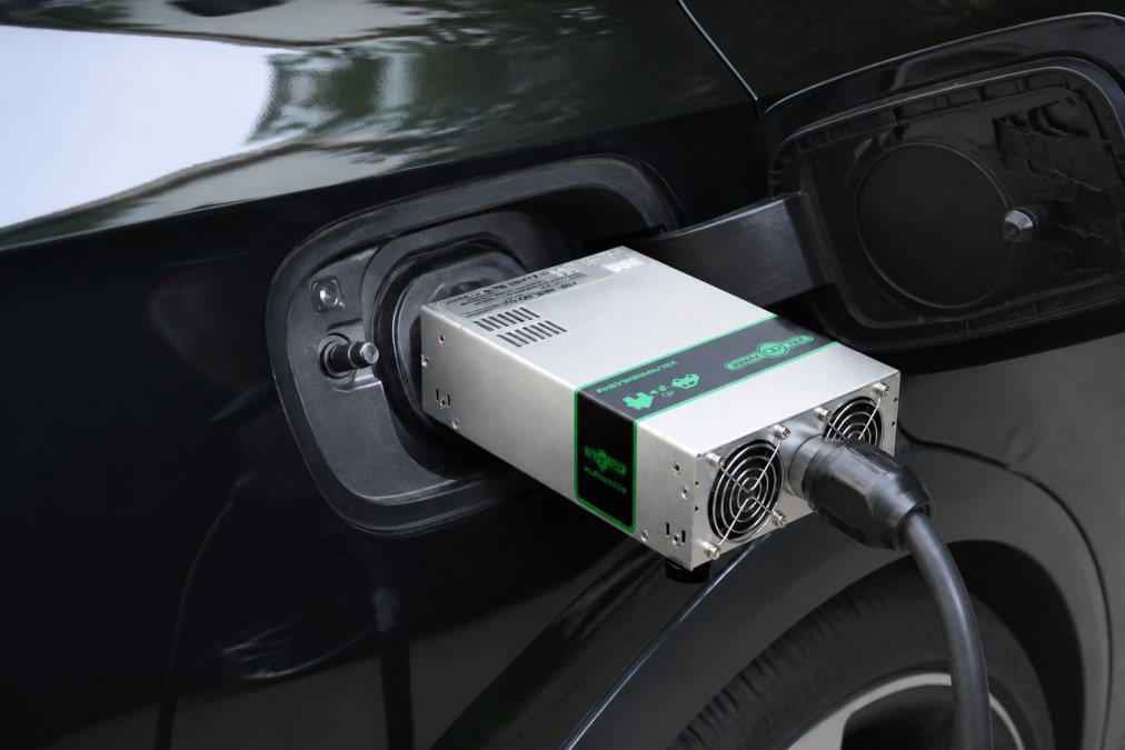 Detailopname van een Type 2-laadpoort op een elektrisch voertuig met een gecertificeerde V2L-adapter aangesloten, waarbij de fysieke veiligheidsaansluitingen en stekkerverbindingen in natuurlijk licht zichtbaar zijn.