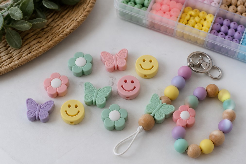 Colorful silicone beads in flower, butterfly, and smiley shapes arranged with a finished keychain and wristlet.