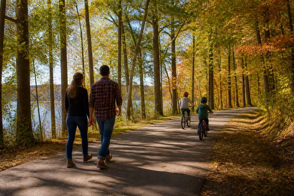 Family cycling on a sunny autumn trail through a wooded park near Slinger WI