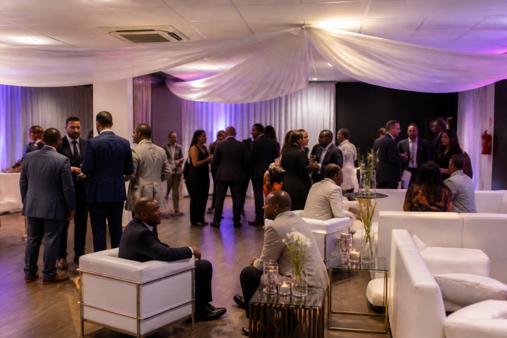 Business professionals networking in an elegant corporate event space with luxurious lounge furniture and lighting.