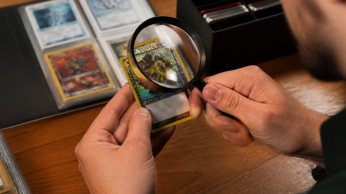 Close-up of hands carefully examining a trading card under bright lighting, checking holographic details and card stock quality with magnifying glass