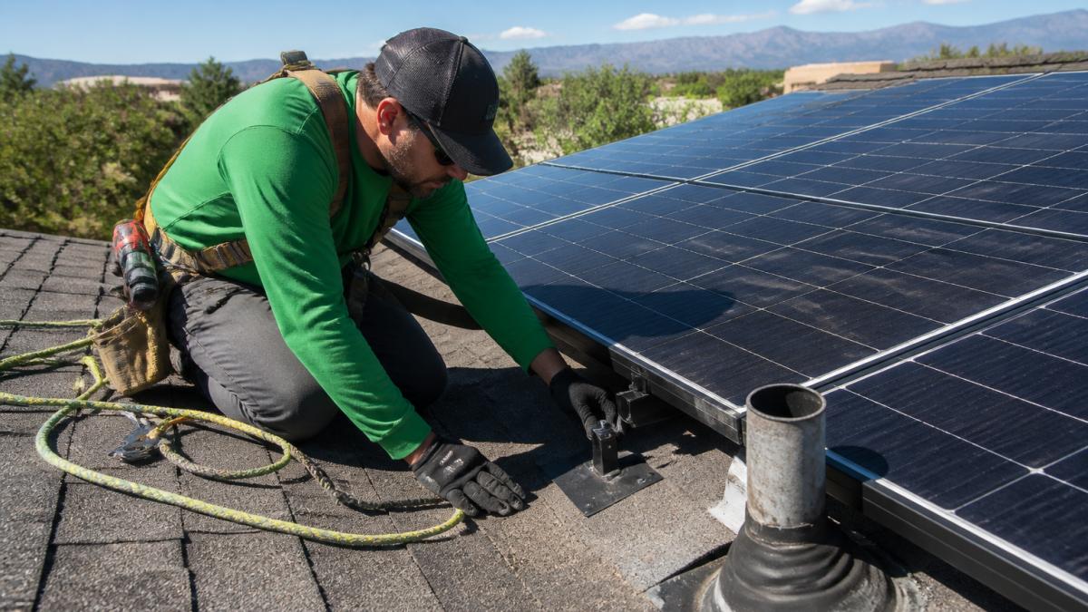 Technician inspecting solar panel mounting hardware before a roof replacement on a sunny day