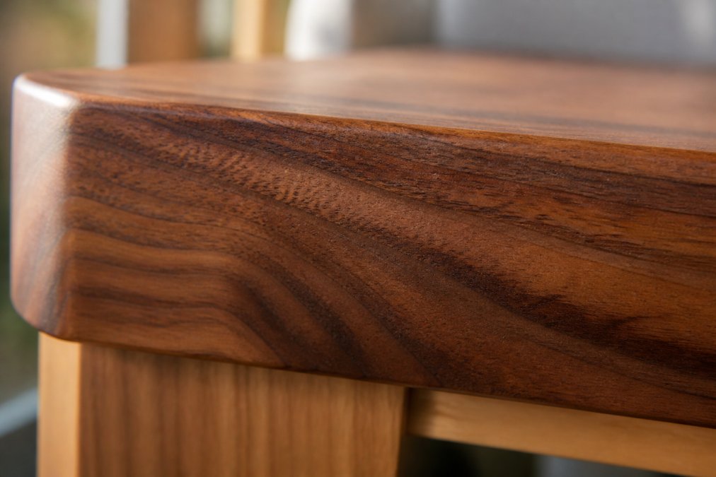 Close-up of wood grain patterns visible on a solid wood furniture edge, showing natural color variation and depth in walnut finish under natural light