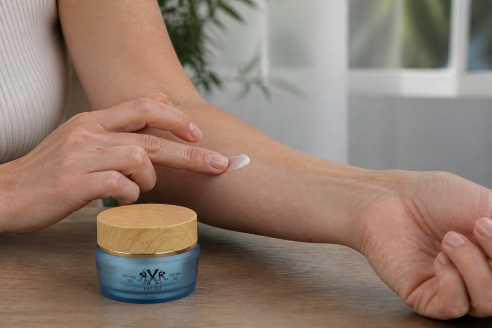 Person performing patch test on inner forearm with small amount of CBD lotion, applying with fingertip in natural daylight, showing proper testing technique