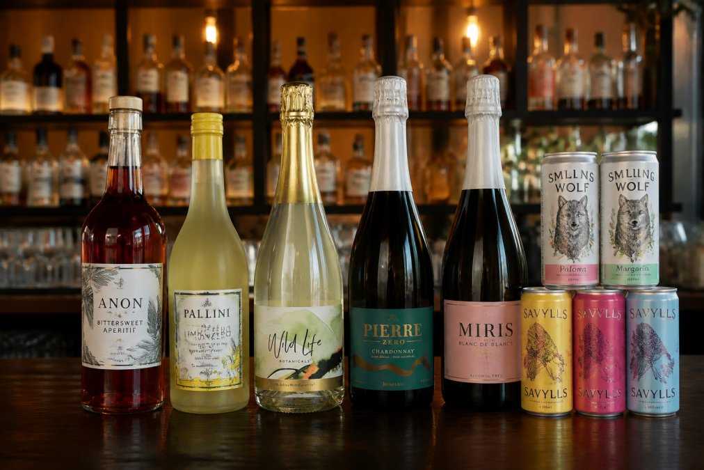 Bottles of sophisticated non alcoholic drinks for parties arranged on a dark wooden bar shelf with warm ambient lighting