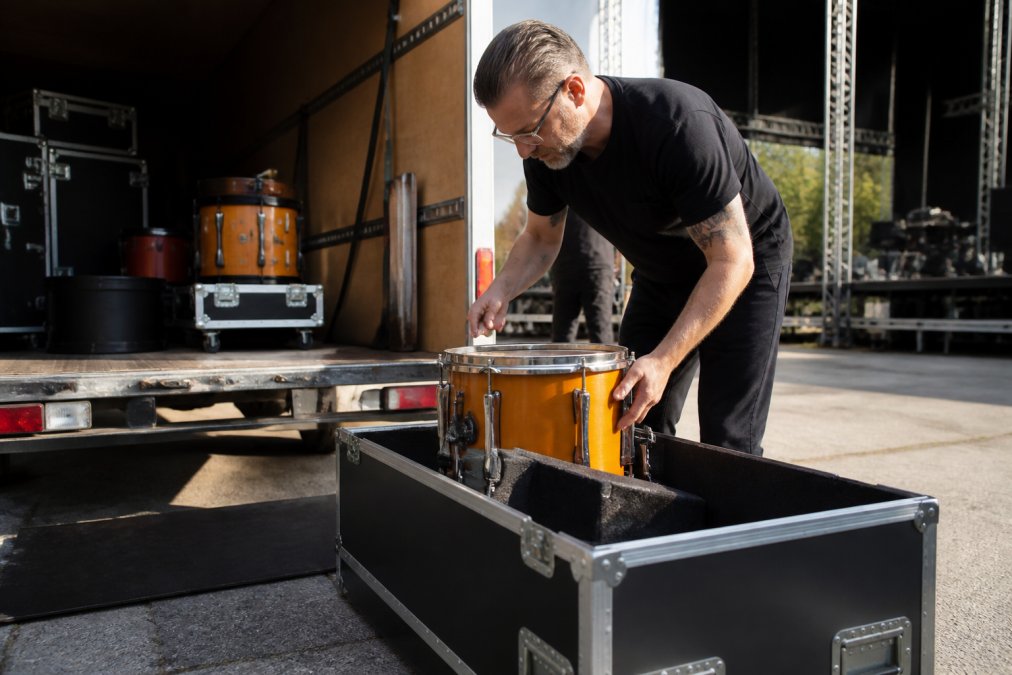 Drum technician carefully packing a rare drum kit into a custom-padded flight case inside a touring van.