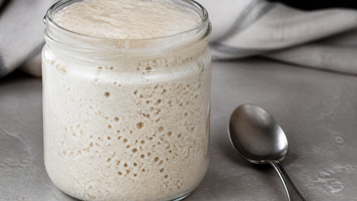 Diagram showing the signs of an active sourdough starter with visible bubbles and a risen surface in a glass jar
