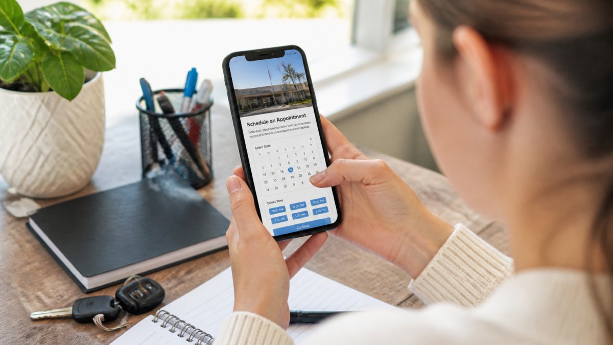 Person using smartphone to schedule an appointment online, with a calendar and DMV office website visible on screen in bright natural lighting