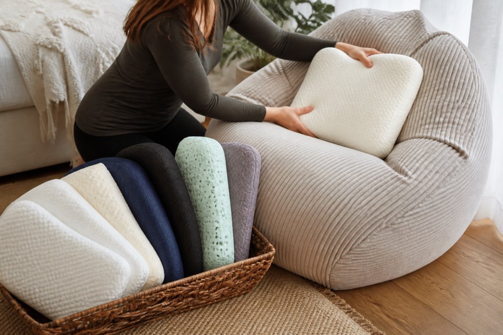 Gros plan montrant différentes textures de matériaux de coussins ergonomiques, avec une personne ajustant délicatement le soutien lombaire sur un pouf pour tester l'adaptation à sa morphologie