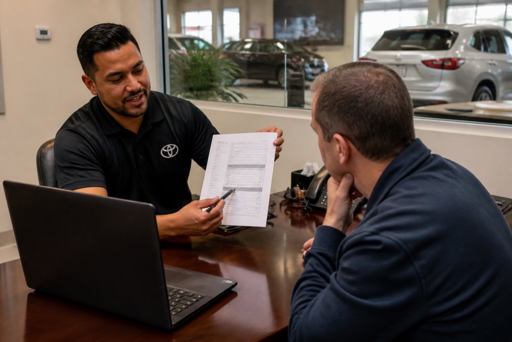 Consultant reviewing a Space City Toyota purchase agreement with a customer to compare dealership pricing models