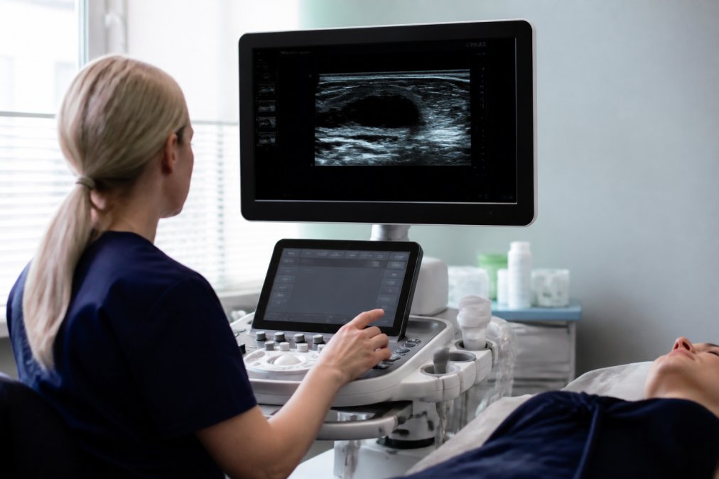 Medizinisches Fachpersonal bedient ein spezial Ultraschallgerät standard in einer hellen Klinik mit Patientendaten auf dem