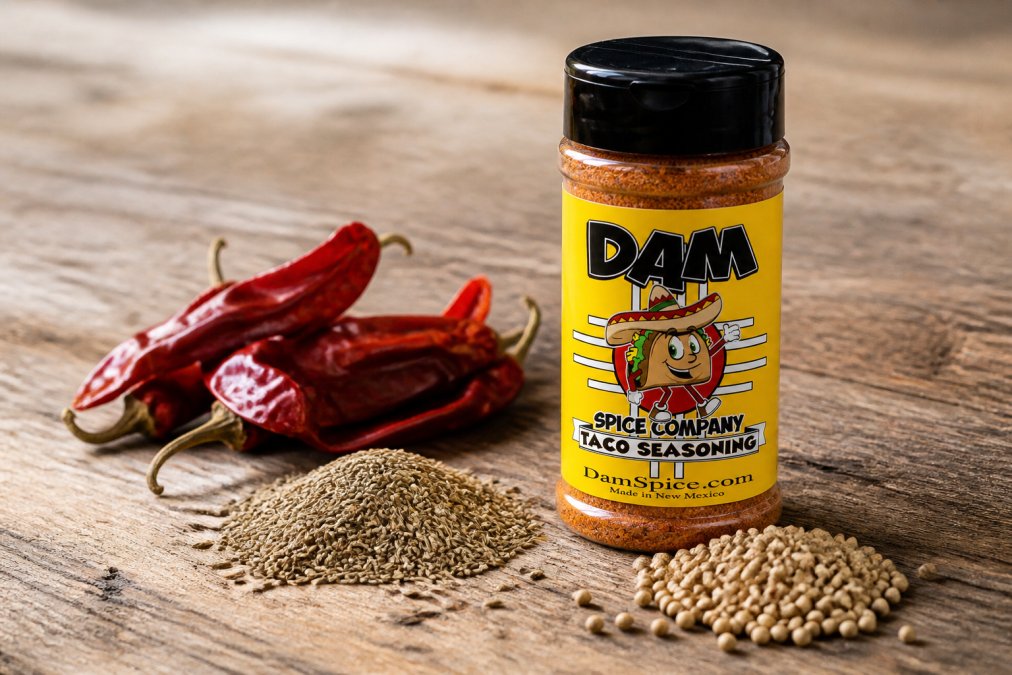 Close-up of spice jar labels showing detailed ingredient lists and no additives, with whole dried chiles, cumin seeds, and coriander seeds scattered on a rustic wooden surface in natural light
