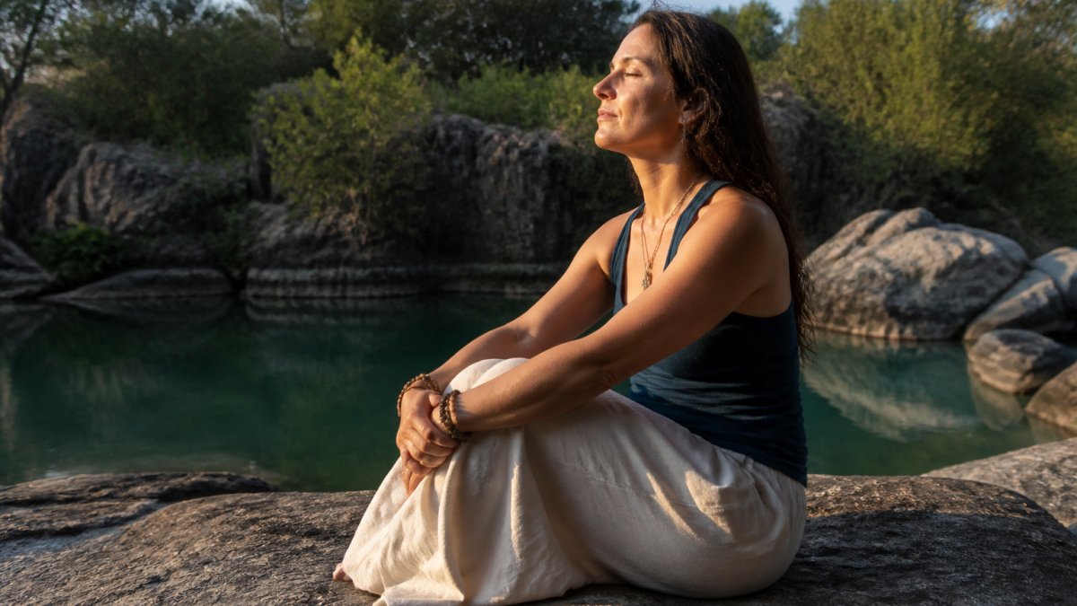 Spiritual Signs Your Crush Is Thinking About You 1 A woman sitting quietly in a peaceful natural setting, appearing calm and centred, with soft natural light suggesting an introspective moment of spiritual awareness