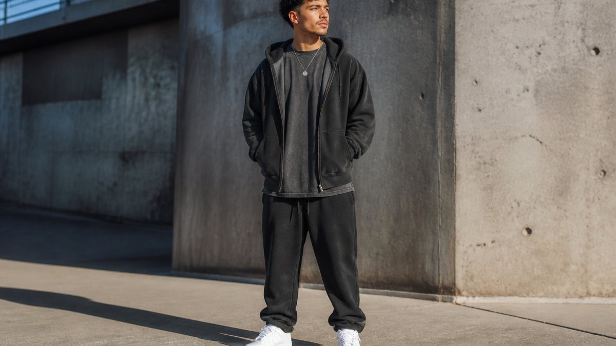 Person wearing an oversized graphic t-shirt and fleece hoodie styled with white sneakers and a simple necklace