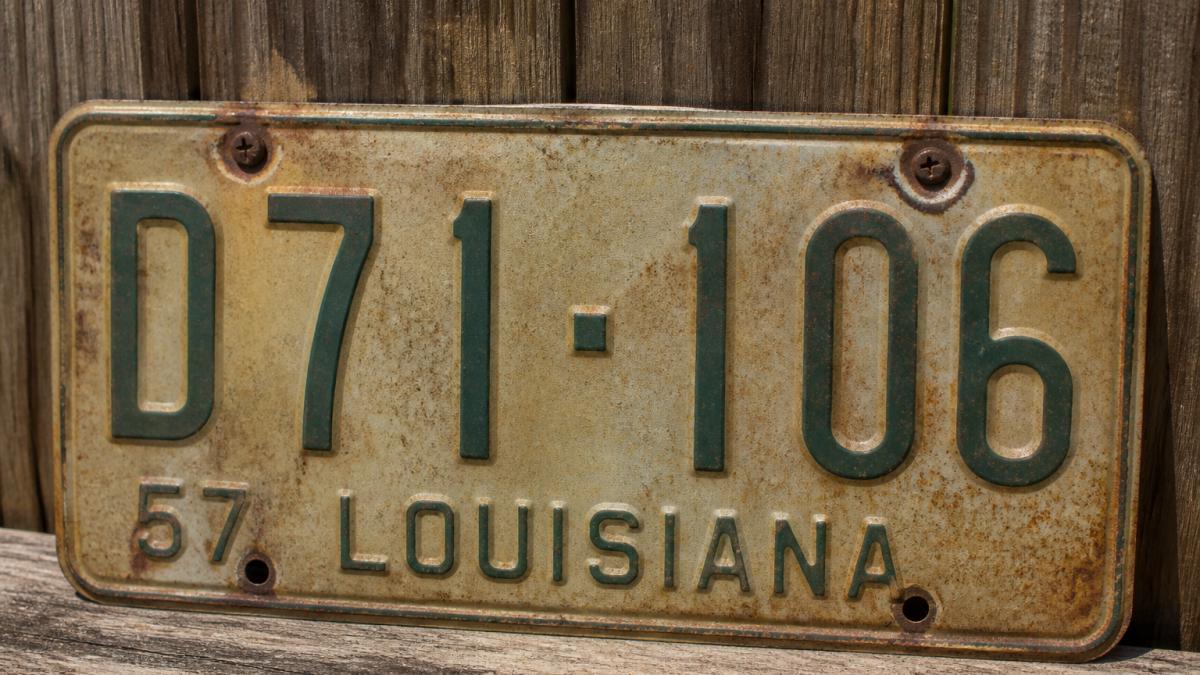Close-up of a vintage Southern license plate showing detailed lettering, rivets, and weathered background color under natural daylight