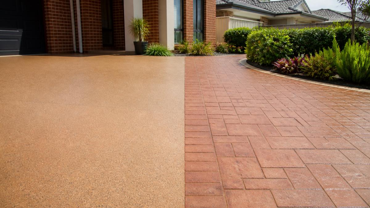 A freshly finished residential driveway in a Perth suburb showing two contrasting sections: one smooth coloured spray-on concrete finish and one stencil concrete section with a brick paver pattern, with a house and garden in the background