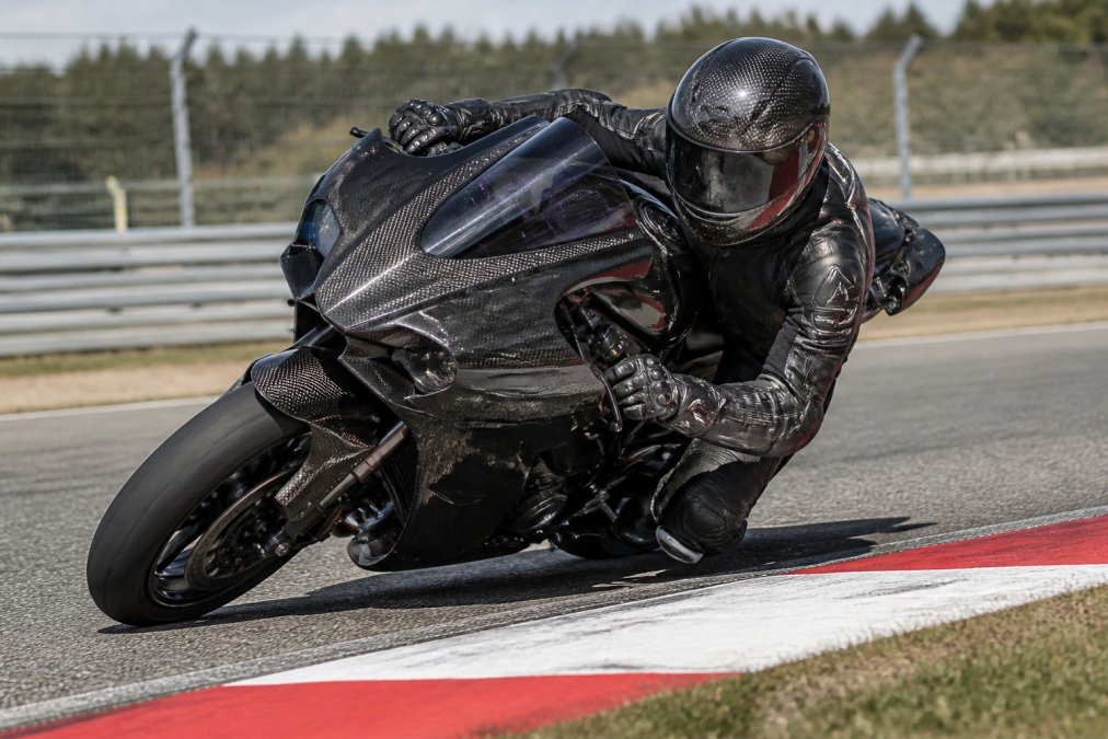 Motorrijder op een performance motor accelererend op een circuit, met focus op dynamische rijpositie en motorprestatie