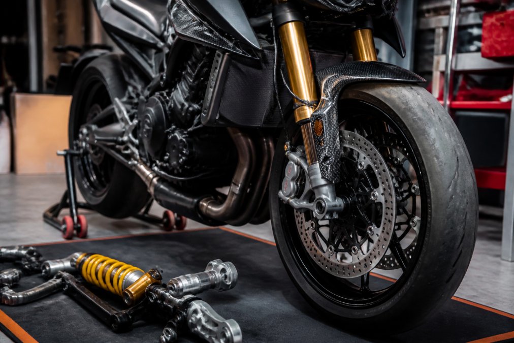 Close-up van een performance motormotor met zichtbare Ohlins-ophanging en aangepaste remschijven in een werkplaats