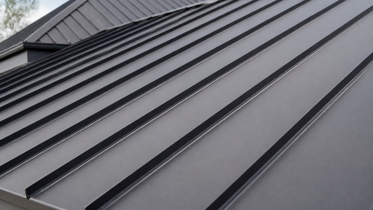 Close-up detail of a standing seam metal roof showing the raised vertical seams and interlocking panel design with clean, unbroken lines running the length of the roof surface