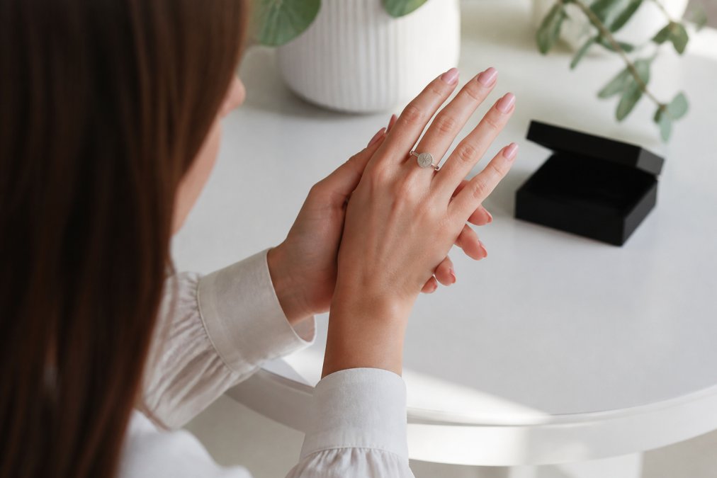Eine Frau bewundert ihren glänzenden Sternzeichen-Ring als Geschenk, während die feine Gravur im Licht erstrahlt.