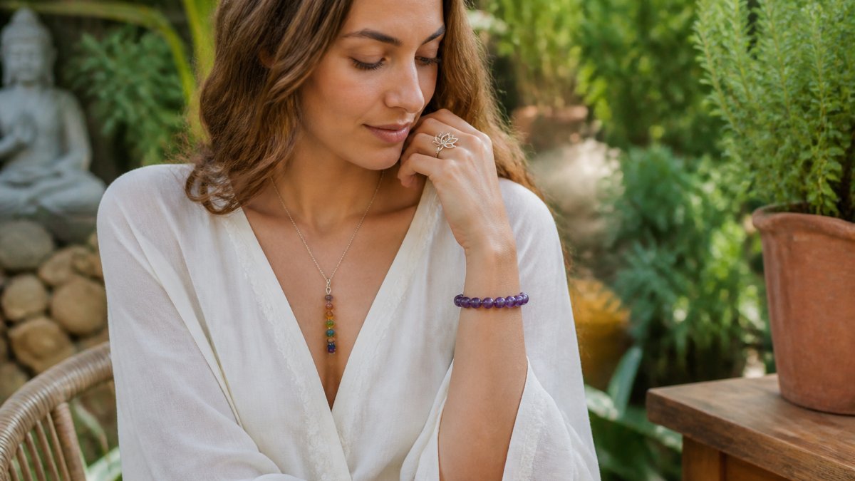 Vrouw draagt stijlvolle spirituele sieraden in een rustige tuin met veel groen en natuurlijk daglicht.