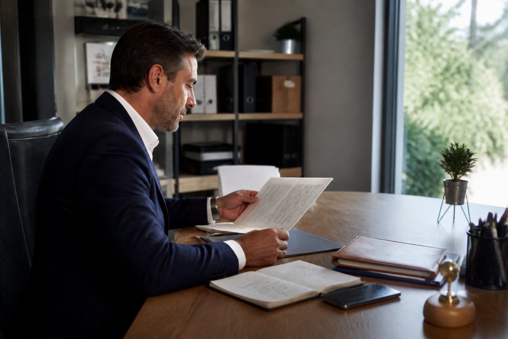 Professionnel de l'immobilier consultant un écran d'ordinateur affichant une interface de gestion client, avec notes et données de prospects visibles