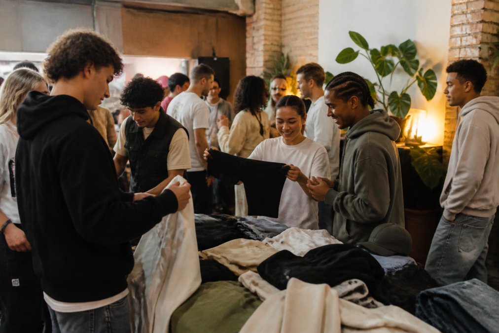 Groep diverse streetwear-enthousiastelingen op community event in Eindhoven, jongeren in trendy outfits die kleding uitwisselen en netwerken, warme verlichting, gemoedelijke sfeer