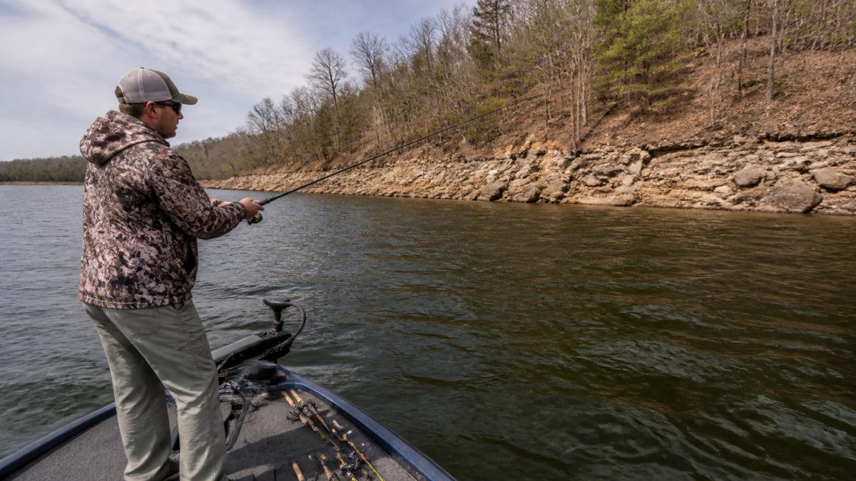 Angler using forward-facing sonar to guide a crankbait along a rocky bass fishing ledge