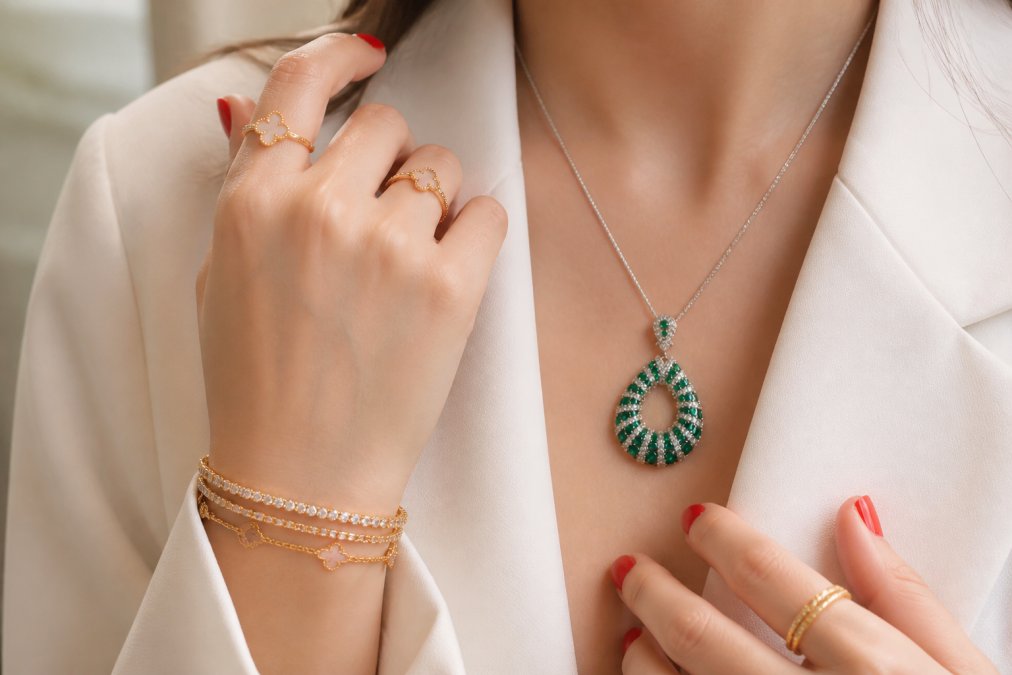 Close-up of layered gold necklaces and stacked rings on a woman's hands, showing how minimalist pieces combine for an intentional, sophisticated look
