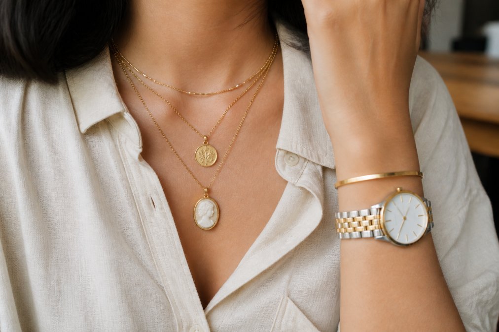 Woman's wrist and neck showing layered vintage necklaces with delicate chains and a modern minimalist watch, demonstrating how vintage and contemporary pieces work together in natural daylight