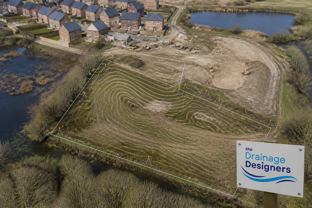 Aerial view of a residential development site showing existing property boundaries, surrounding water features, and topographical contours with survey markers visible